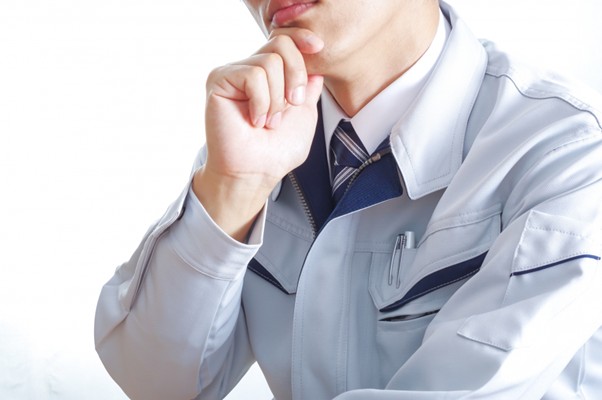 考え事をする作業服の男性