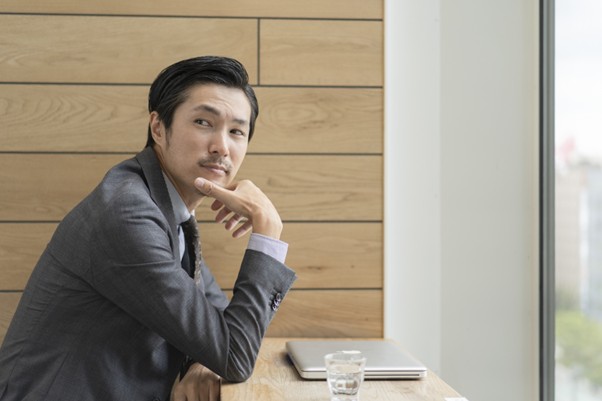 座ってひじをつき周りを見るビジネスマン