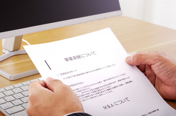 PC前で書類を持つ人