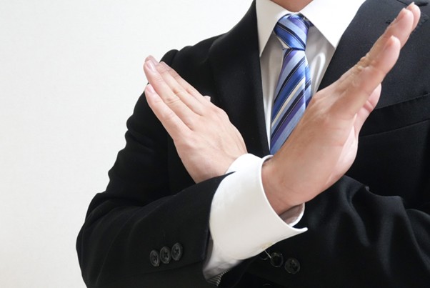 手で✕をつくるビジネスマン