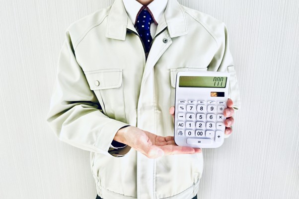 電卓を示す作業服の男性