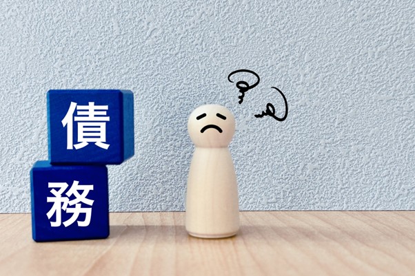 悩む人形と債務の積み木