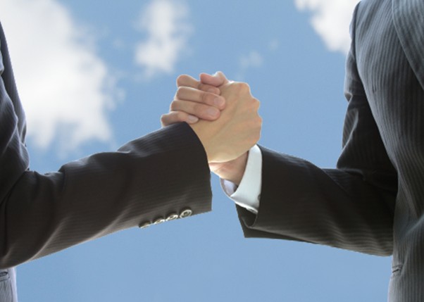 握手するビジネスマンと青空