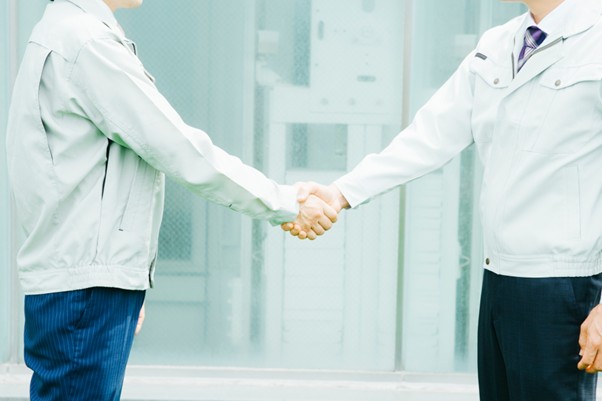 握手する作業服の男性