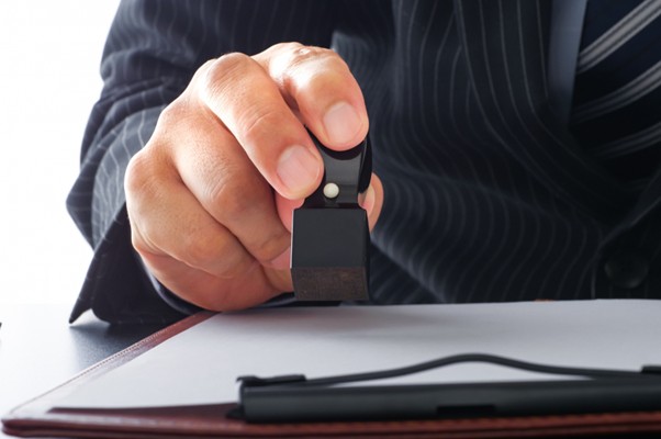 書面に印鑑を押すビジネスマン