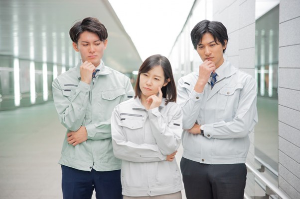 考える作業服姿の男女