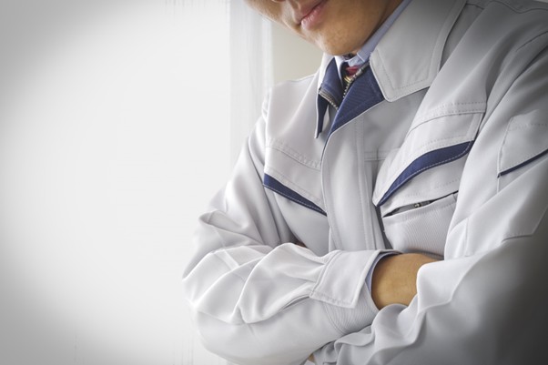 腕を組む作業服の男性
