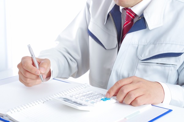 電卓を使う作業服の男性