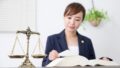 天秤と書籍を読む女性弁護士