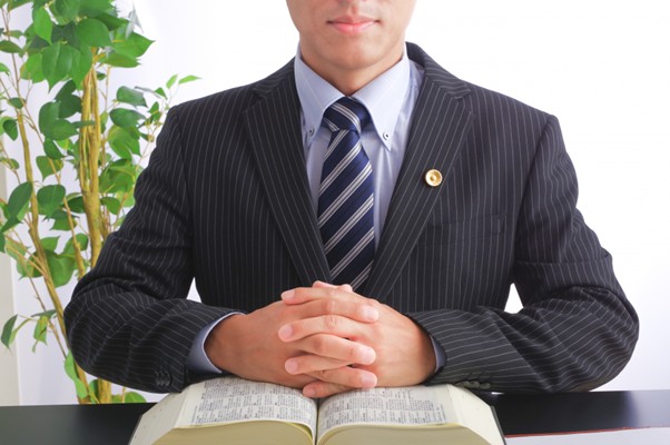 本の上で手を組む弁護士