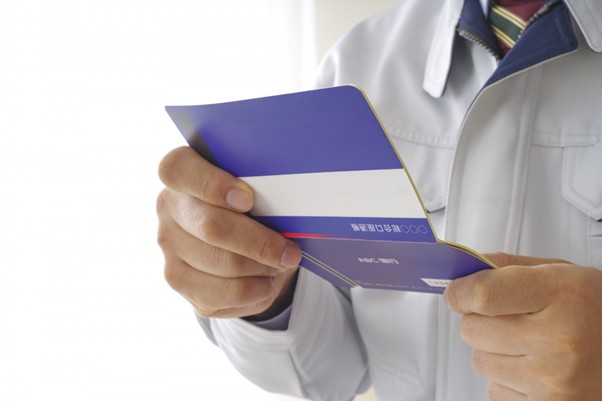 通帳を開く作業服の男性